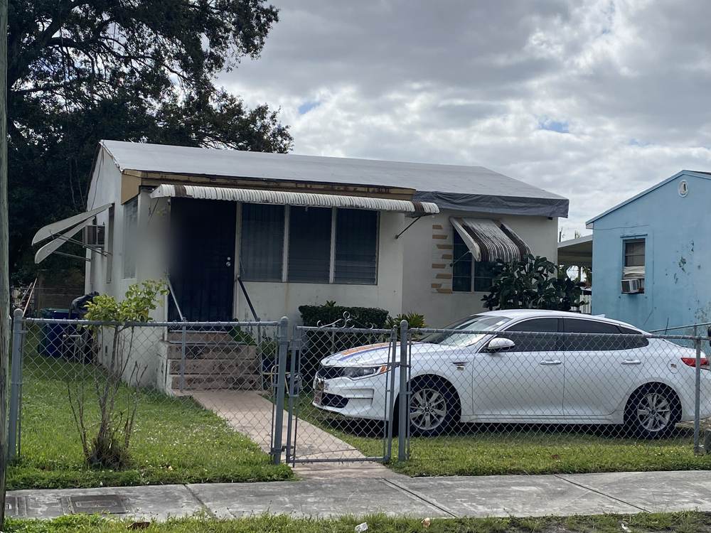 A Brownsville house before renovation, with a sagging porch overhang and a failing roof