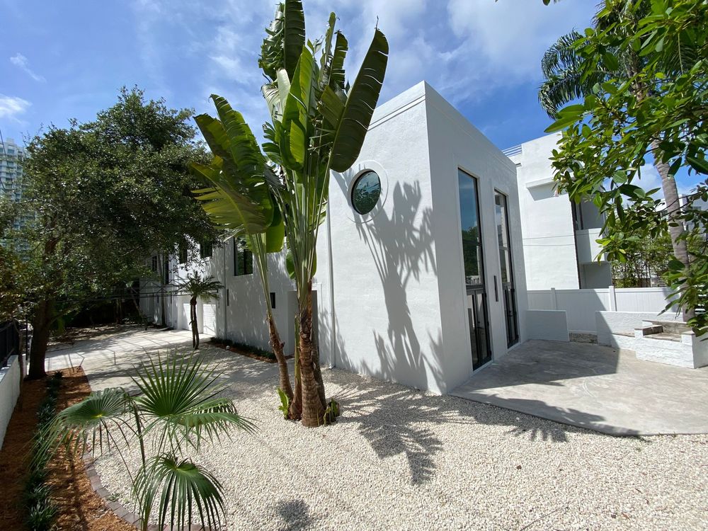 The same Coconut Grove house after a full gut renovation, refinished in flat white stucco with black-framed glass