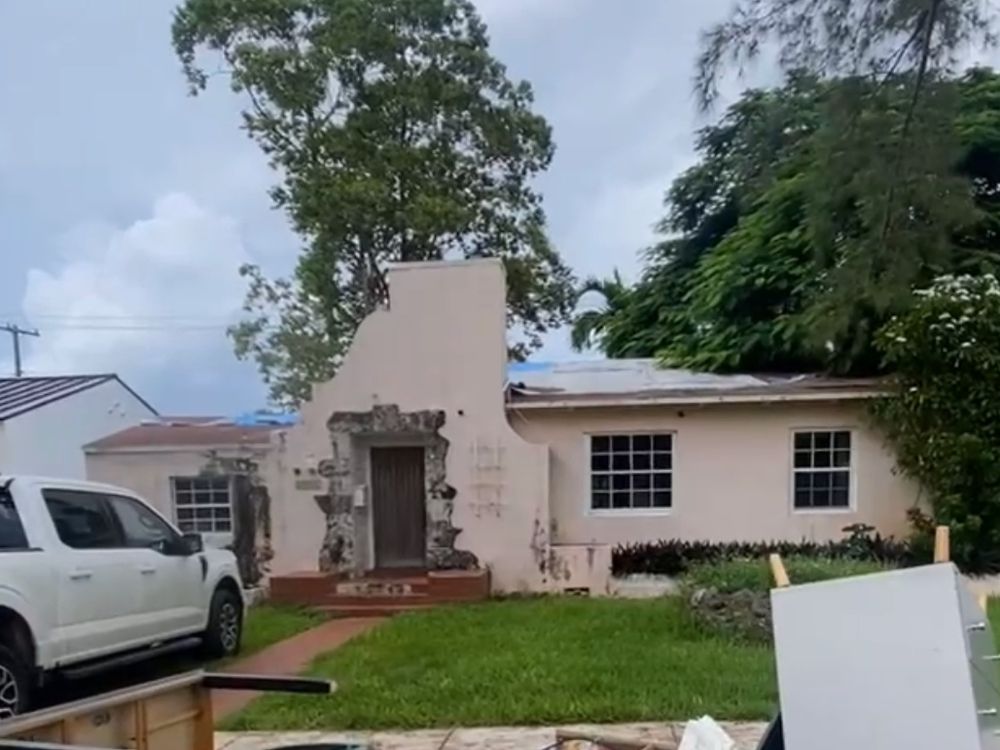 A Shenandoah house before renovation, with a rusted roof and a broken coral rock facade